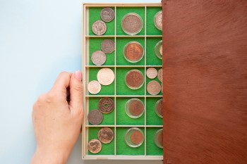 Skrzyneczka z filcowanymi miejscami na monety. Część monet w kapslach